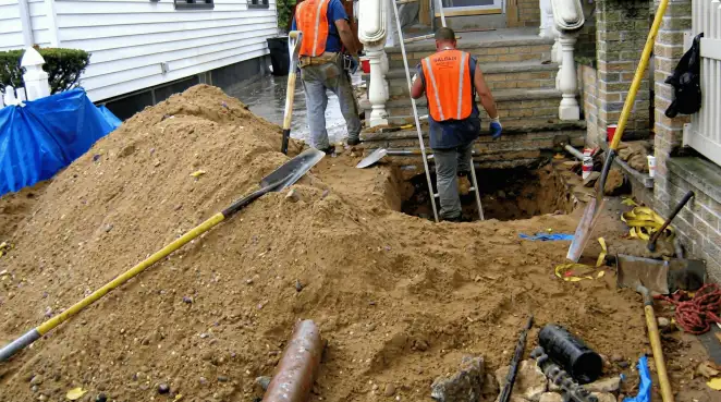 Contractors performing foundation protection and exterior drainage excavation near residential home steps in Pueblo, CO